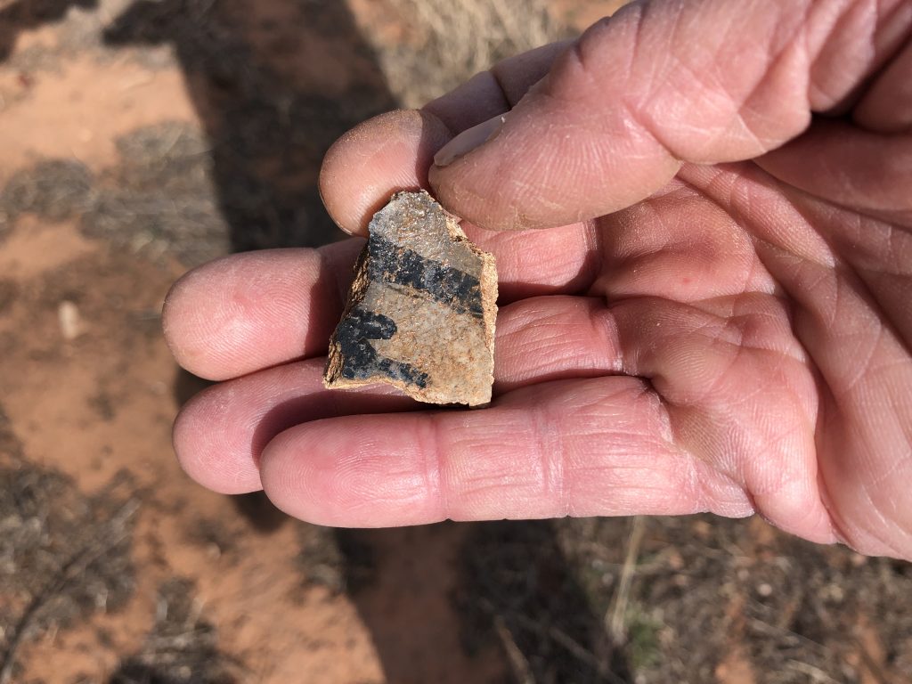 Photo of a small sherd of pottery painted with black markings.