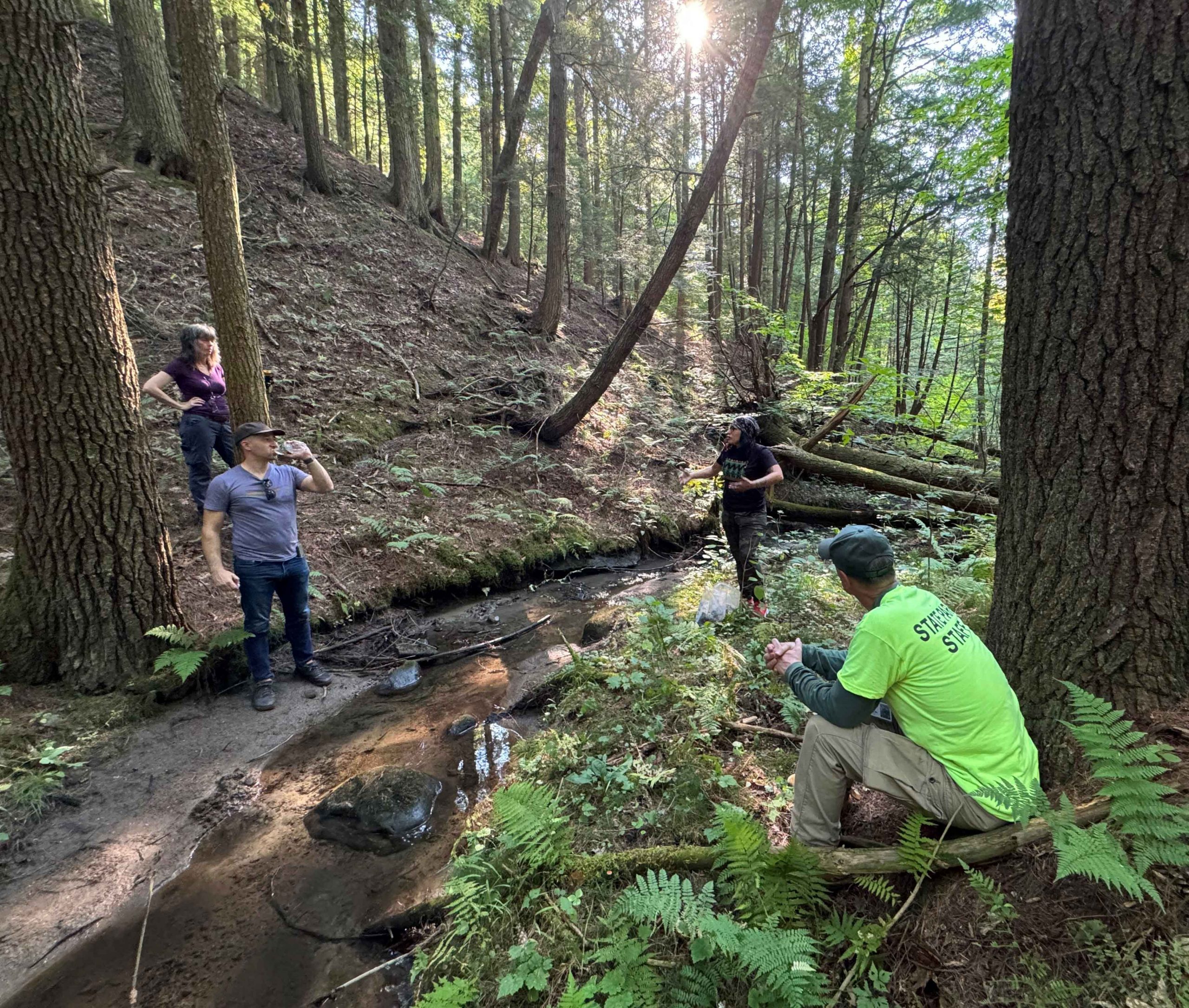 Staff from the New York State Museum and Kanien’keha:ka potter Natasha Smoke Santiago (center, right) take a break from collecting clay from a small stream that borders the Garoga site. Photo: Jonathan Lothrop