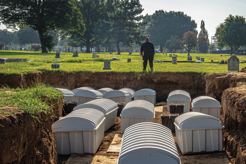 J.J. Kavin Ross looks over new burial containers, each holding the remains of individuals exhumed during the 2021 field season, as they are prepared for reburial. At the time, Ross, a descendant of massacre survivors, was chair of the Tulsa Race Massacre Graves Investigation Public Oversight Committee. In 1997, Ross’ father, former state Rep. Don Ross, was the author and co-sponsor of House Joint Resolution 1035 which created the Oklahoma Commission to Study the Tulsa Race Riot of 1921. The results of that study served as the forerunner to the current investigation. Kavin Ross passed away on May 8, 2023. Photo courtesy of the City of Tulsa.