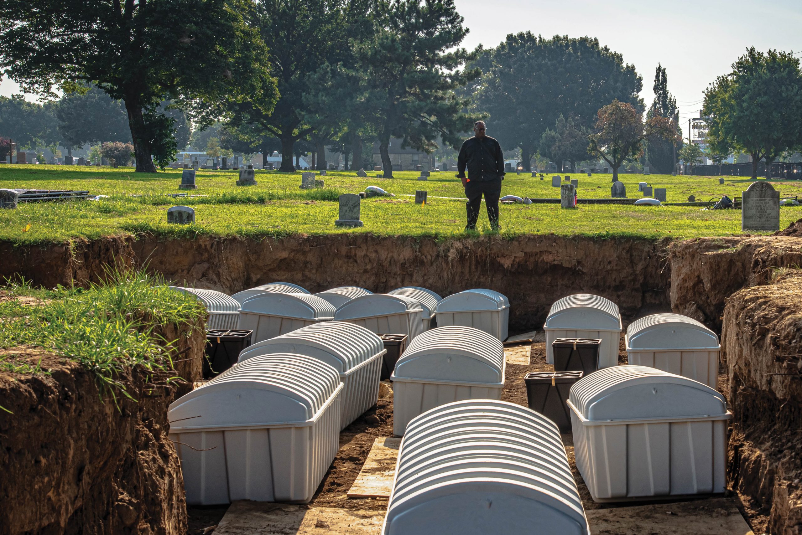 J.J. Kavin Ross looks over new burial containers, each holding the remains of individuals exhumed during the 2021 field season, as they are prepared for reburial. At the time, Ross, a descendant of massacre survivors, was chair of the Tulsa Race Massacre Graves Investigation Public Oversight Committee. In 1997, Ross’ father, former state Rep. Don Ross, was the author and co-sponsor of House Joint Resolution 1035 which created the Oklahoma Commission to Study the Tulsa Race Riot of 1921. The results of that study served as the forerunner to the current investigation. Kavin Ross passed away on May 8, 2023. Photo courtesy of the City of Tulsa.